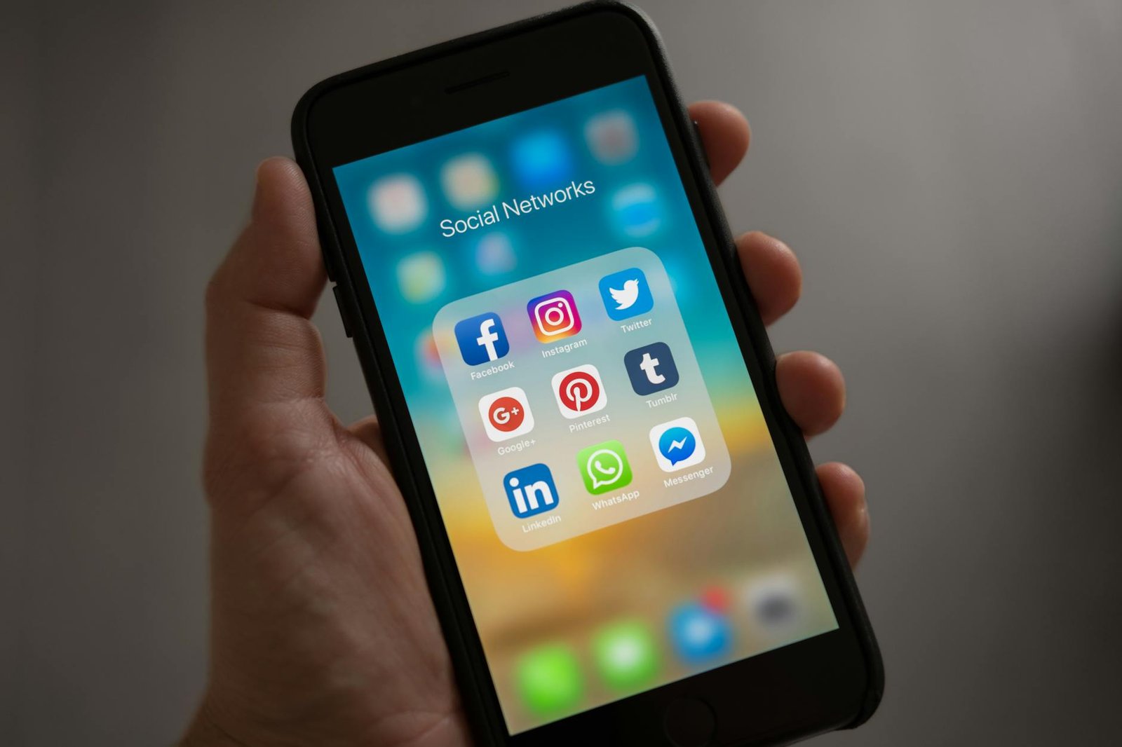 person holding iphone showing social networks folder- growing instagram audiences